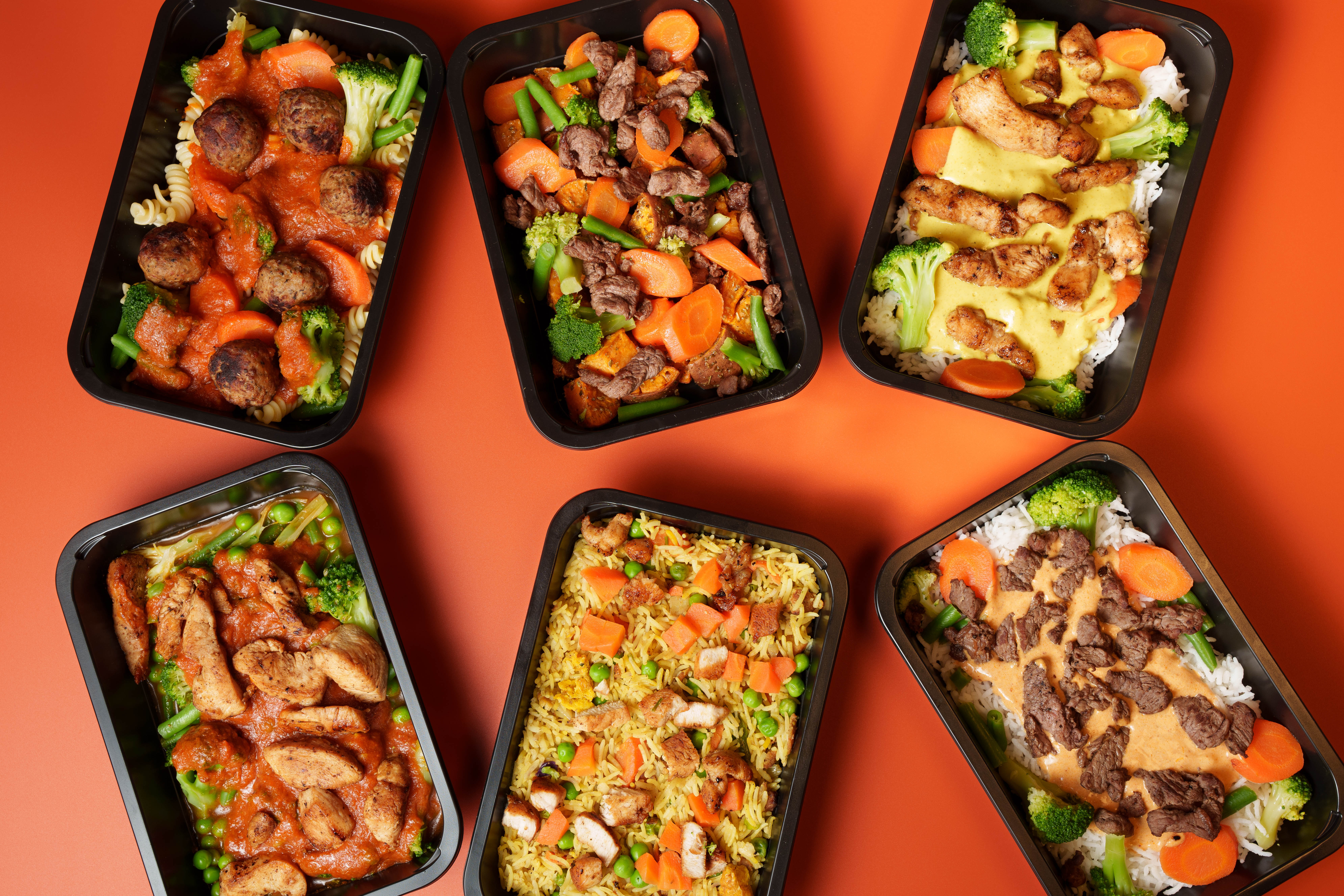 Prepared meal boxes photographed on a warm orange background